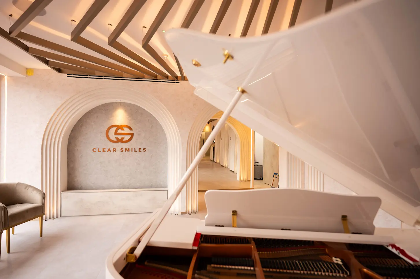 A Grand piano in the foreground in a luxury dental practice with Clear Smiles on the background wall